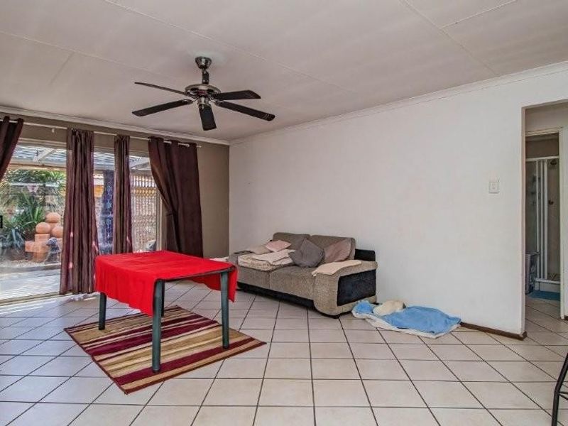 Spacious living area featuring tiled flooring, a ceiling fan, and sliding glass doors providing access to the outdoor patio area.