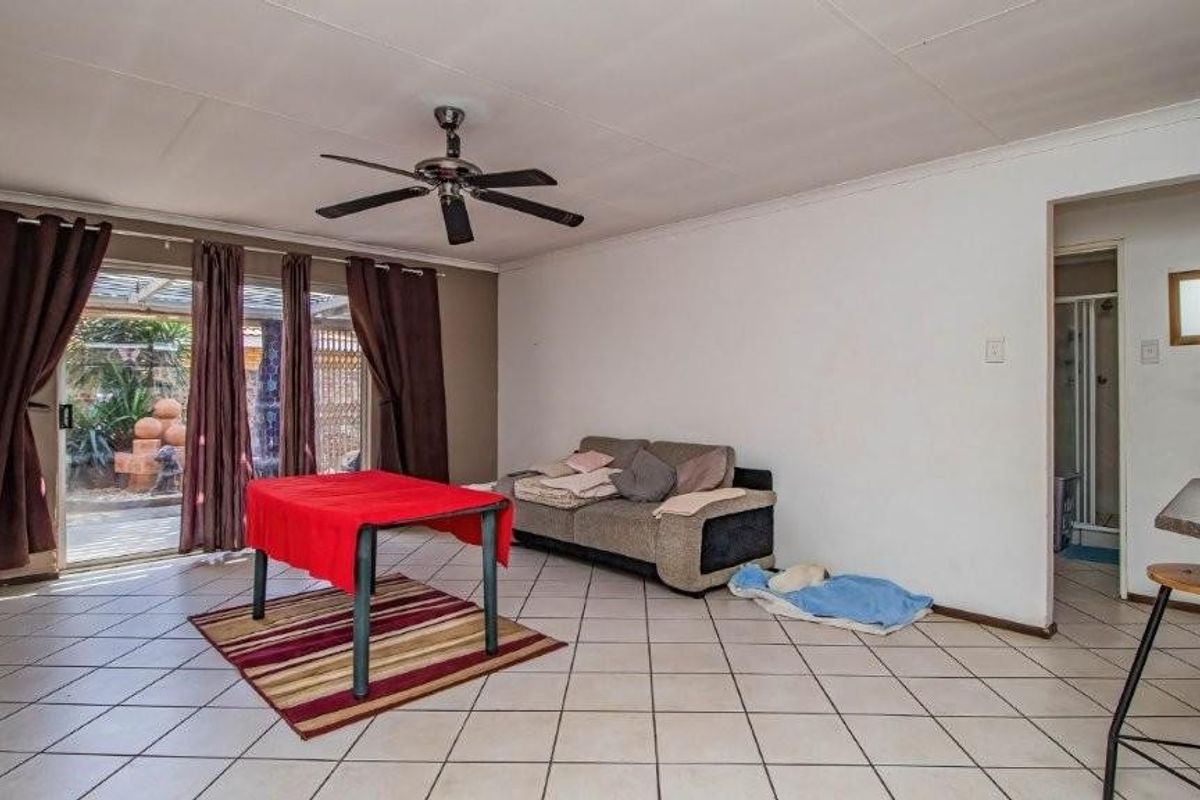 Spacious living area featuring tiled flooring, a ceiling fan, and sliding glass doors providing access to the outdoor patio area.