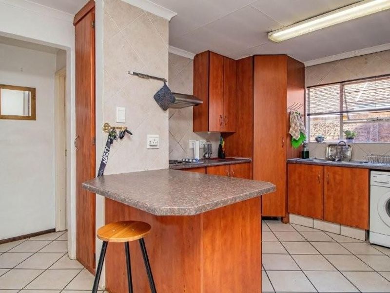 A functional kitchen featuring wood-look cabinetry, tiled flooring, a breakfast nook, and integrated laundry appliance space.