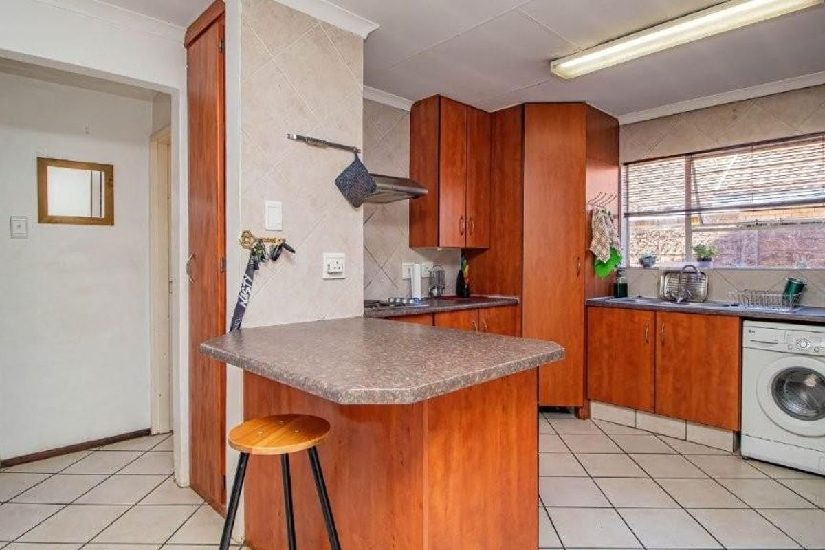A functional kitchen featuring wood-look cabinetry, tiled flooring, a breakfast nook, and integrated laundry appliance space.