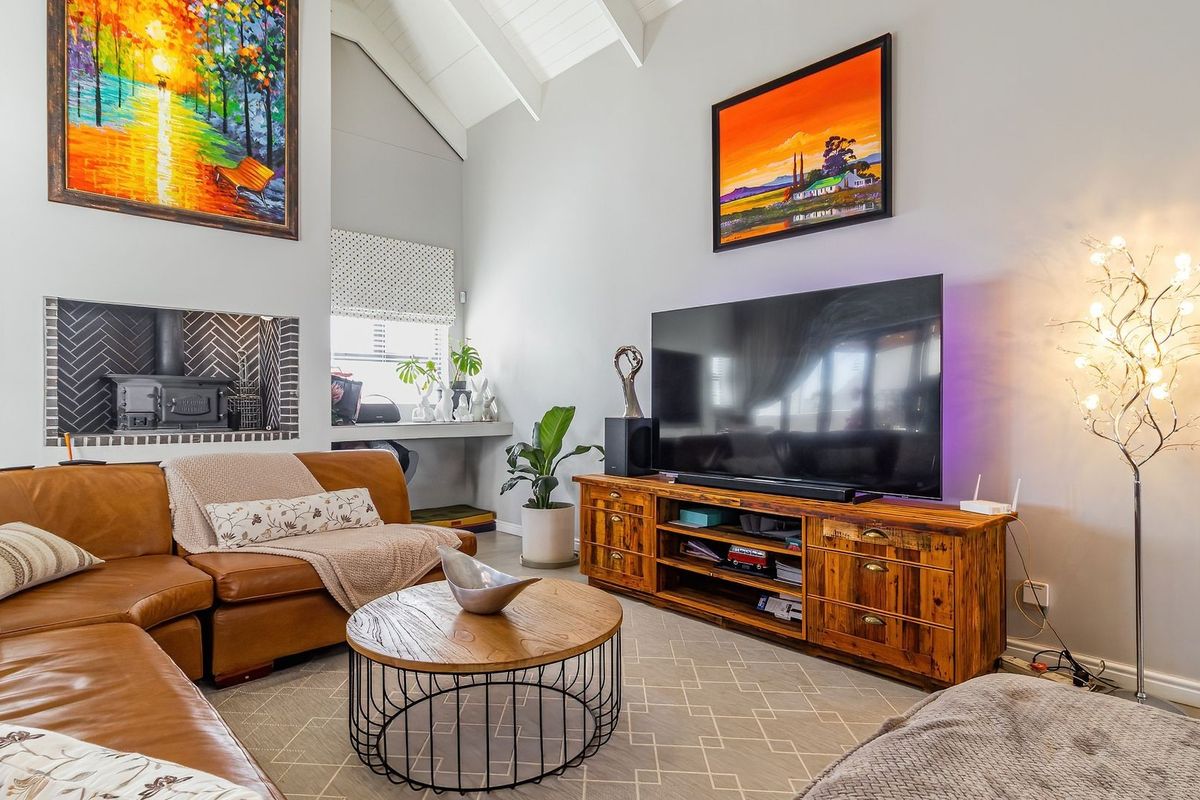 A bright living room featuring a high vaulted ceiling with exposed rafters and a stylish built-in fireplace with herringbone tile detailing.