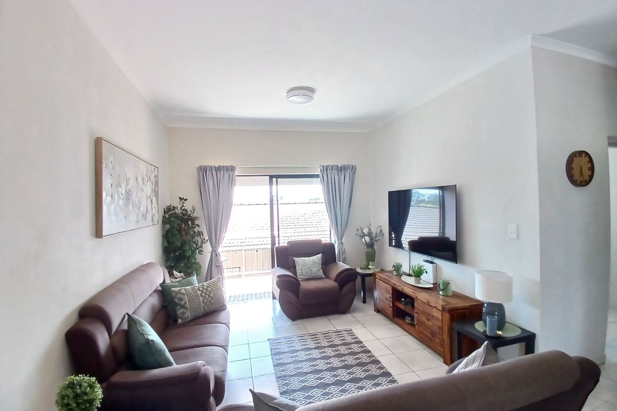 A well-maintained living room featuring tiled flooring and a sliding glass door that provides access to an outdoor area.