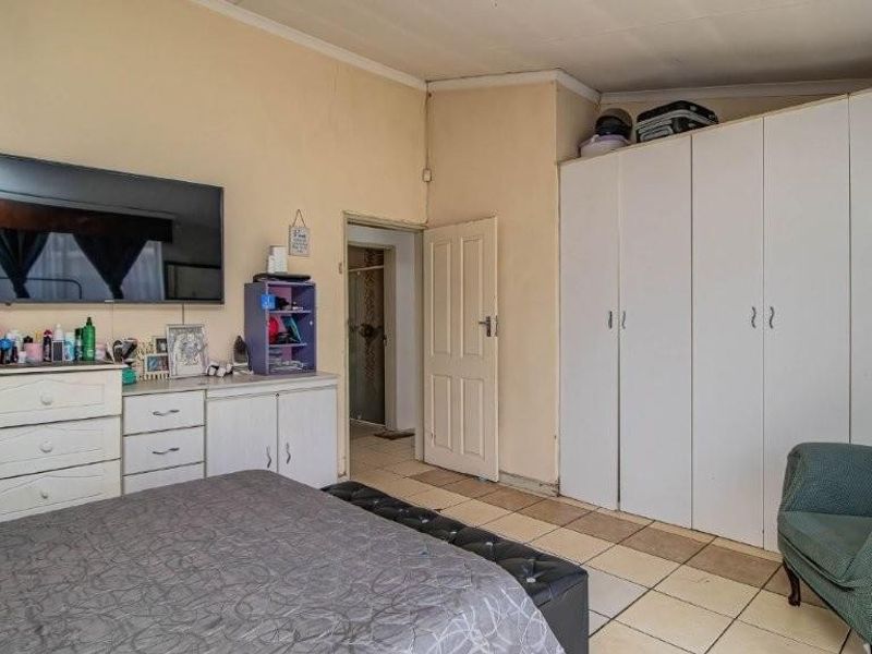 A bedroom featuring built-in cupboards and tiled flooring, requiring cosmetic updates to improve the overall aesthetic and condition of the space.