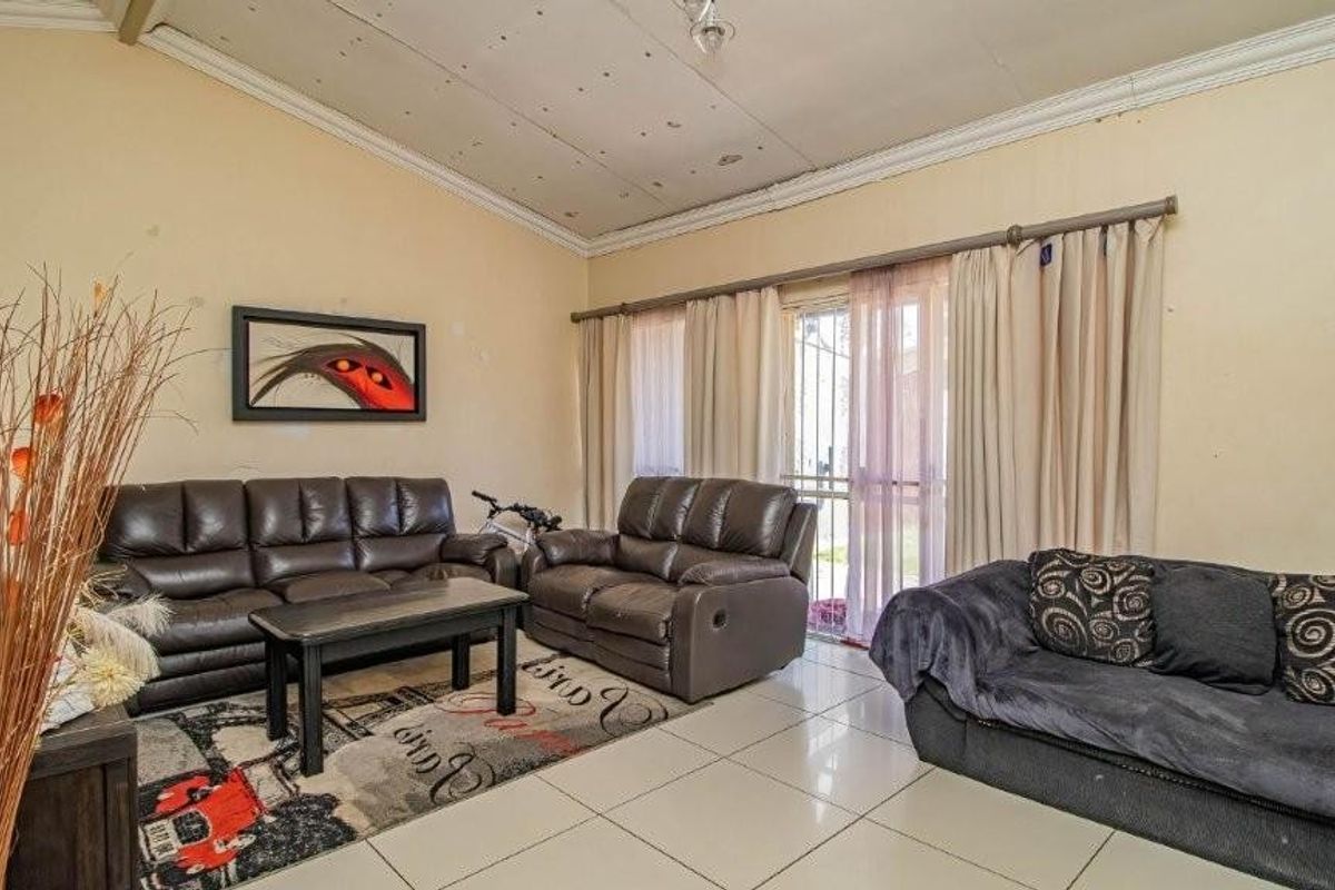 A living room featuring tiled flooring and a sliding glass door leading to the exterior, with visible wear on the walls and ceiling.