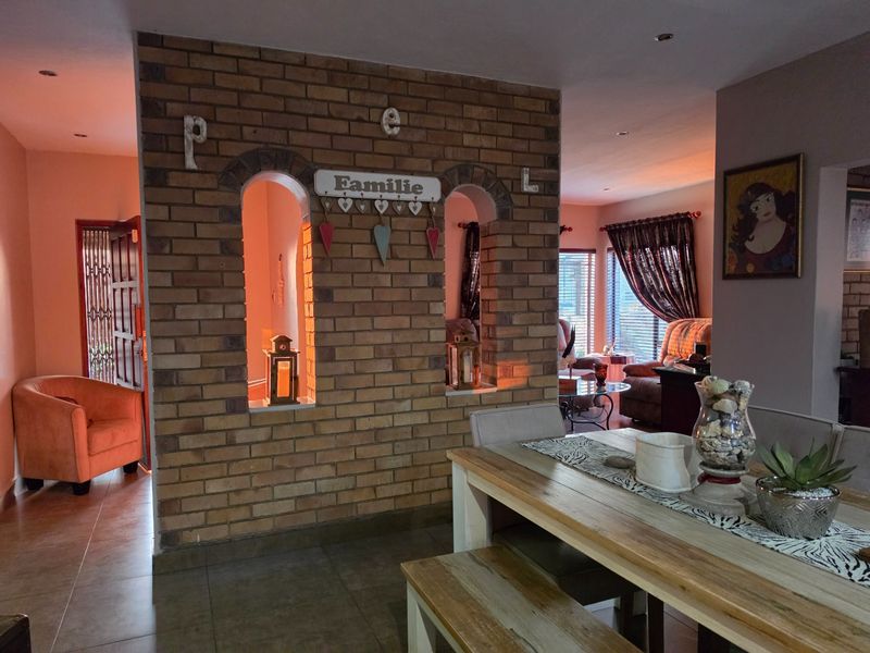 Open plan living and dining area featuring a distinctive exposed brick partition wall with arched openings and modern recessed lighting.