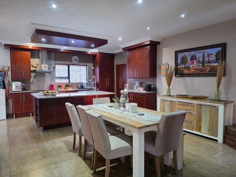 Spacious open-plan kitchen and dining area featuring dark wood cabinetry, granite countertops, a central island, and modern recessed lighting.