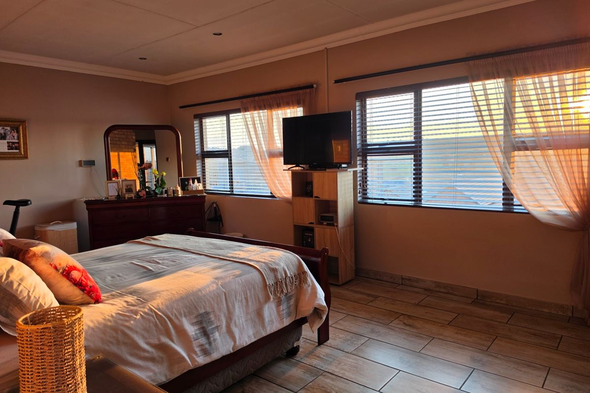 Spacious bedroom featuring tiled flooring, recessed downlighting, and large windows with venetian blinds, offering a comfortable and well-maintained living space.