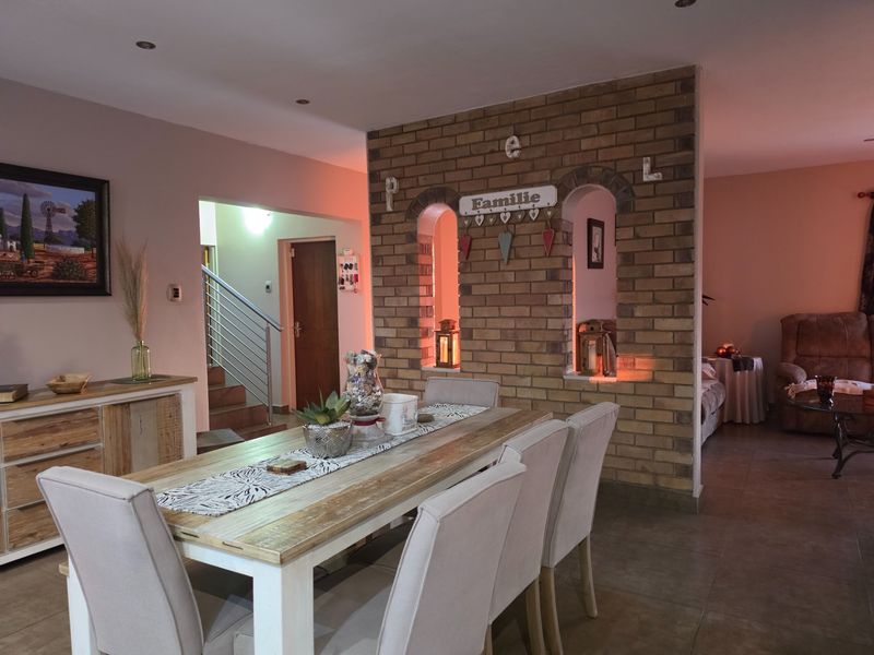 Open plan dining area featuring a distinctive exposed brick partition wall with arched cutouts, tiled flooring, and recessed lighting, connecting to the adjacent living space.