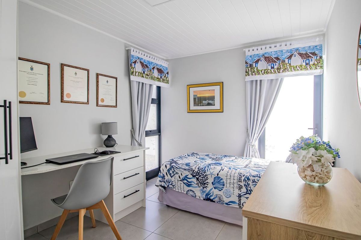 A bright and well-maintained bedroom featuring tiled flooring, a tongue and groove ceiling, and a sliding door providing natural light.