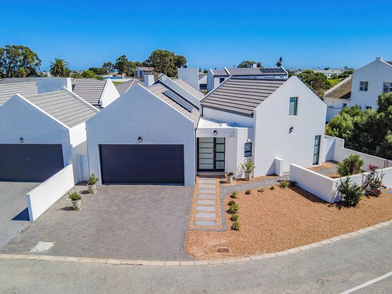 Aerial view of a modern residential property featuring a tiled roof, paved driveway, double garage, and landscaped front garden area.