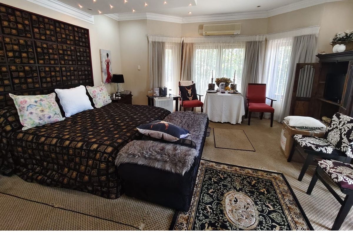 Spacious bedroom featuring a bay window, crown molding, and integrated ceiling lighting, providing a comfortable and well-lit sleeping area.