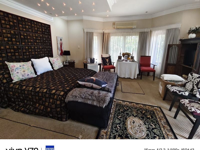 Spacious bedroom featuring a bay window, crown molding, and integrated ceiling lighting, providing a comfortable and well-lit sleeping area.