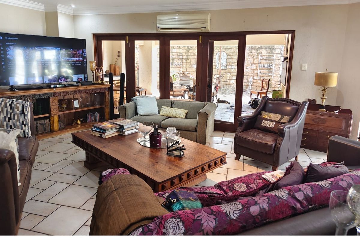 Spacious living room featuring tiled flooring, crown molding, and large wooden folding doors that open to an outdoor patio area.