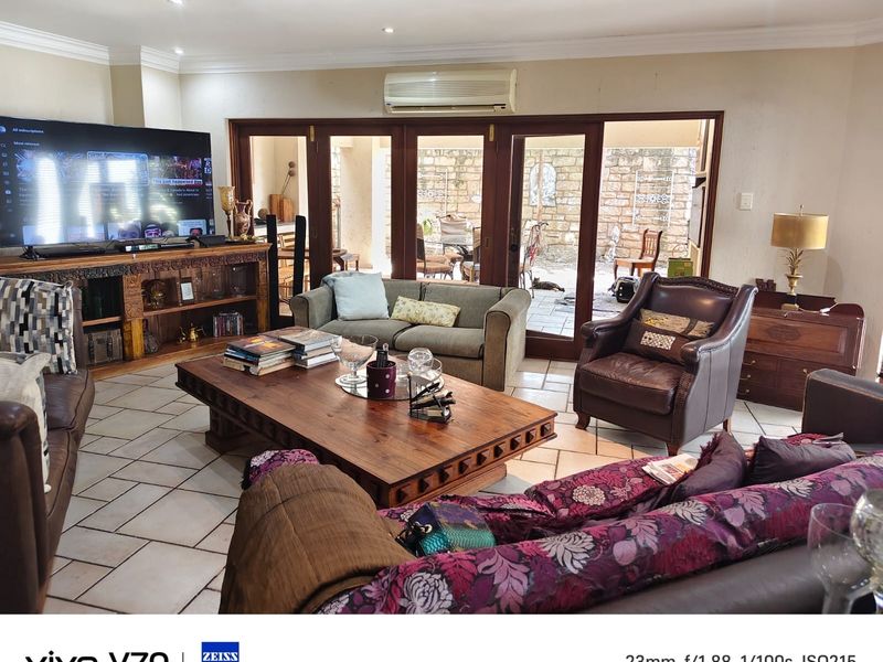 Spacious living room featuring tiled flooring, crown molding, and large wooden folding doors that open to an outdoor patio area.