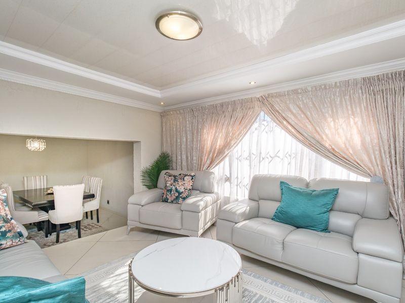 Open plan living and dining area featuring tiled flooring, crown molding, and recessed ceiling lighting, creating a bright and cohesive living space.