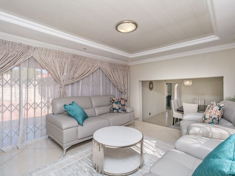 Spacious open-plan living and dining area featuring tiled flooring, a tray ceiling with recessed lighting, and large sliding doors leading to the exterior.