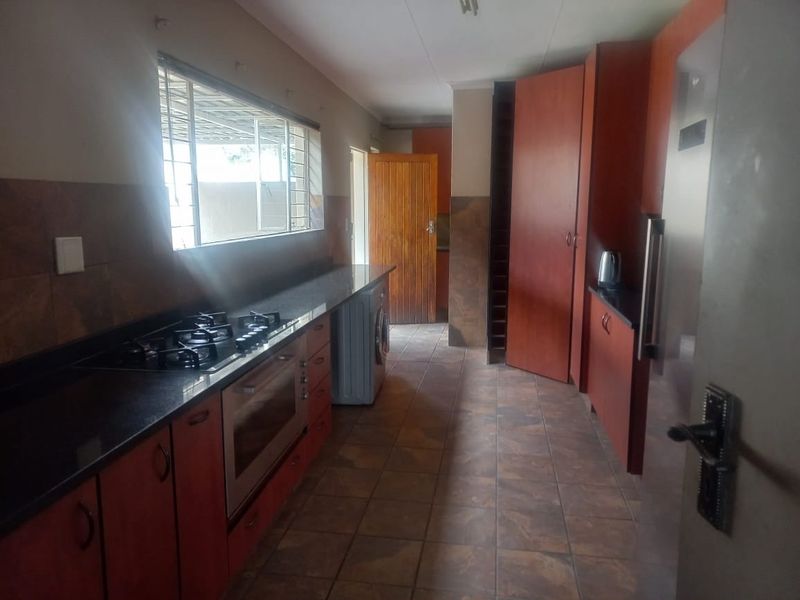 A functional kitchen featuring dark granite countertops, built-in cabinetry, a gas hob, and an integrated oven with tiled flooring throughout.