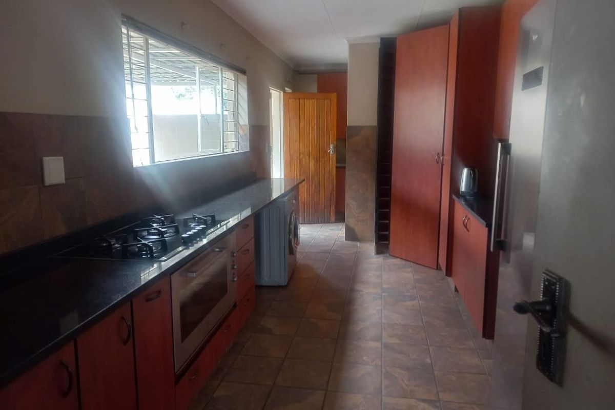 A functional kitchen featuring dark granite countertops, built-in cabinetry, a gas hob, and an integrated oven with tiled flooring throughout.