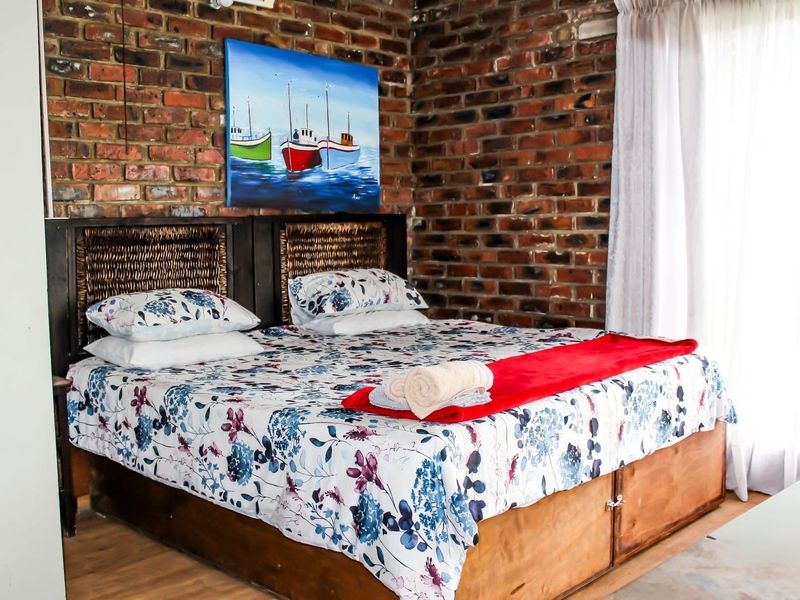 A bedroom featuring a rustic exposed brick feature wall and laminate flooring, providing a warm and textured aesthetic.