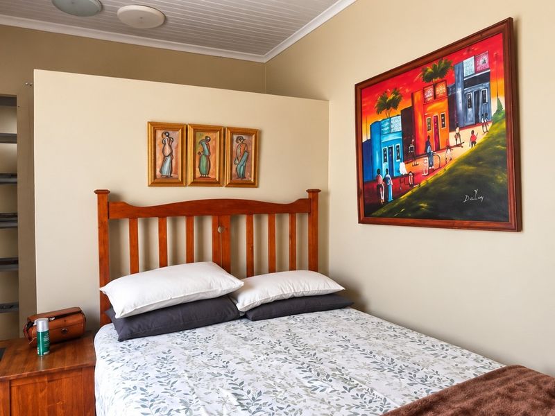 A cozy bedroom featuring timber flooring, a tongue and groove ceiling, and a built-in shelving unit.