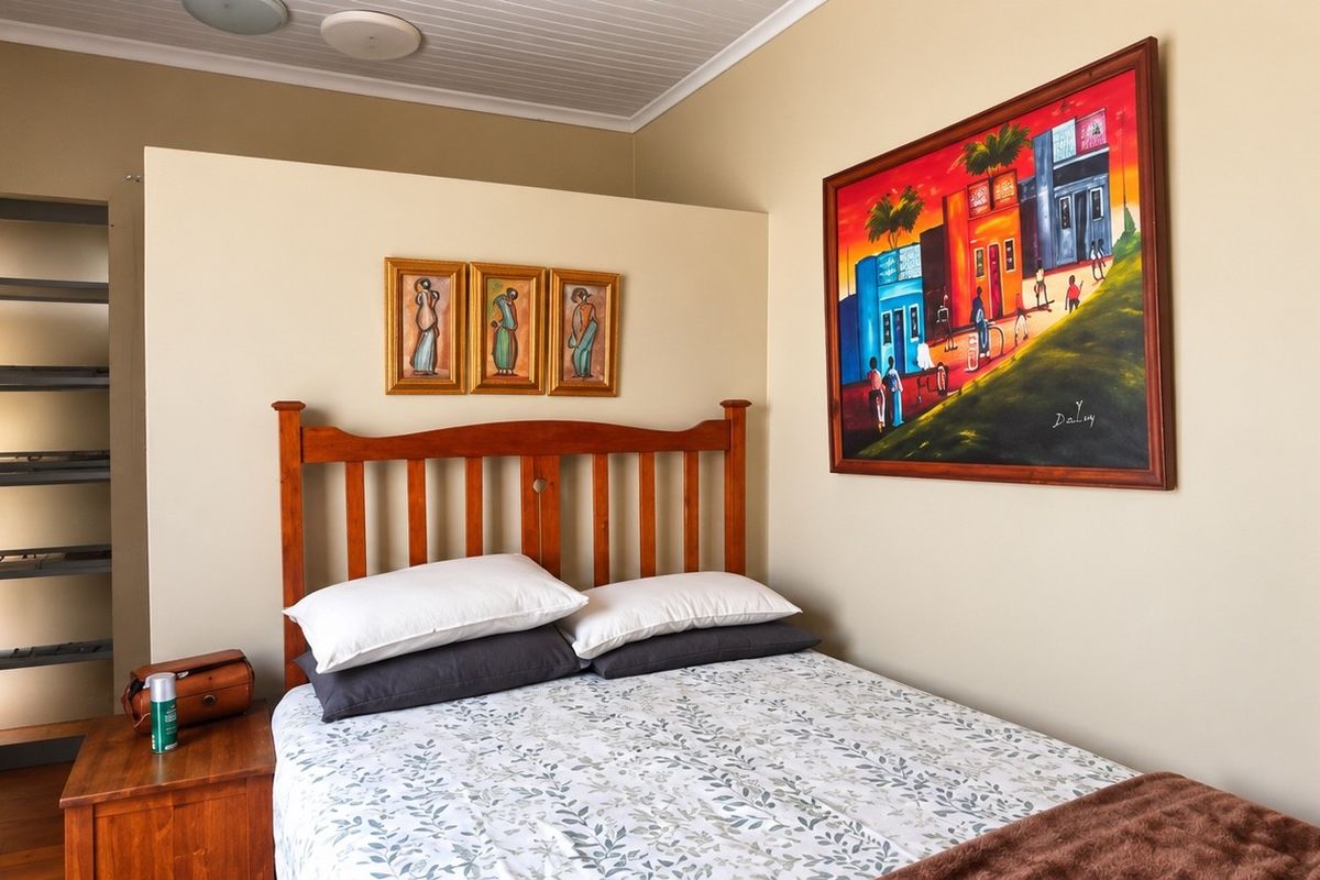 A cozy bedroom featuring timber flooring, a tongue and groove ceiling, and a built-in shelving unit.
