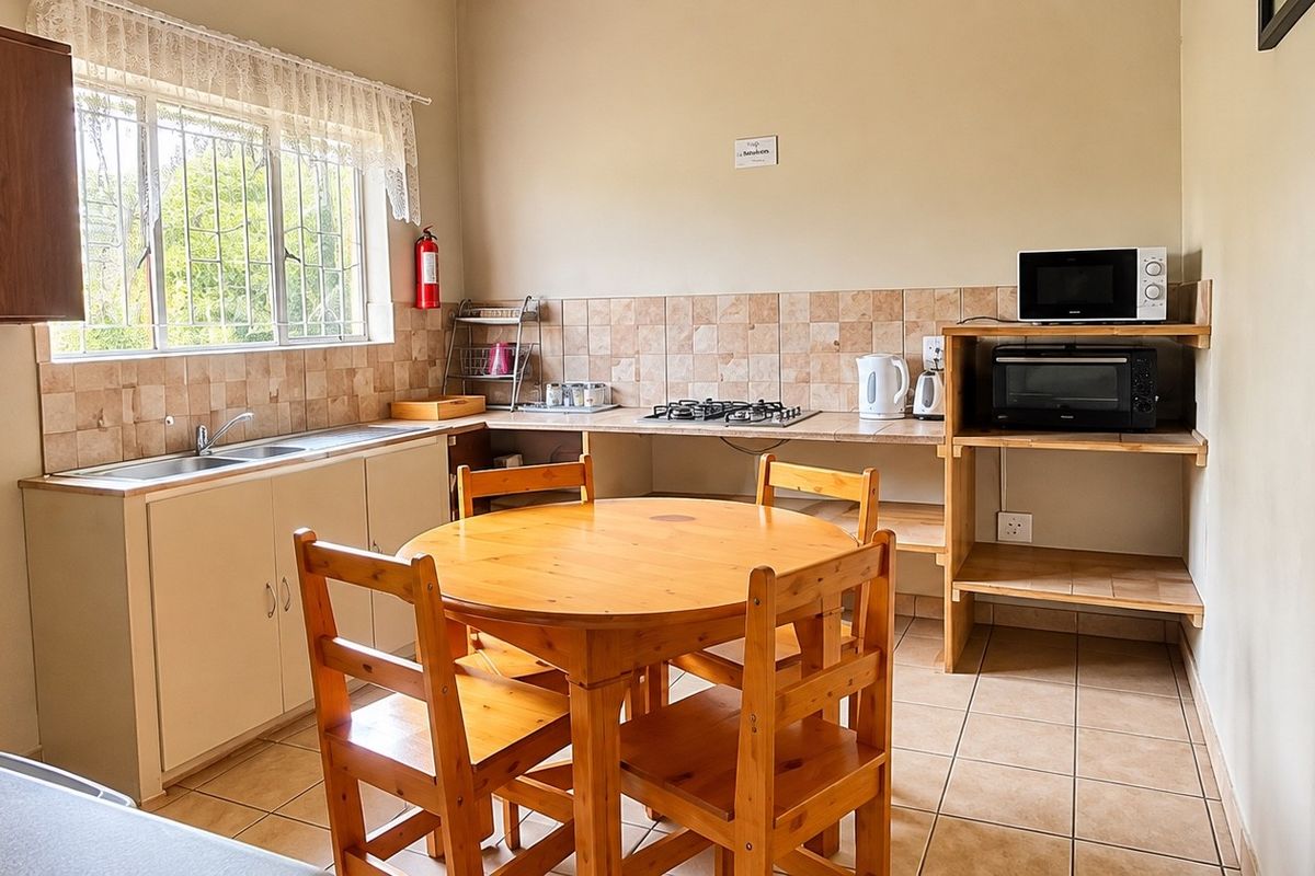 A functional kitchen featuring built-in cabinetry, a double basin sink, tiled backsplash, and a gas hob, with tiled flooring throughout.
