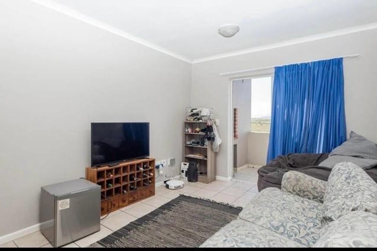 A functional living room featuring tiled flooring and a sliding glass door providing access to an outdoor balcony area.