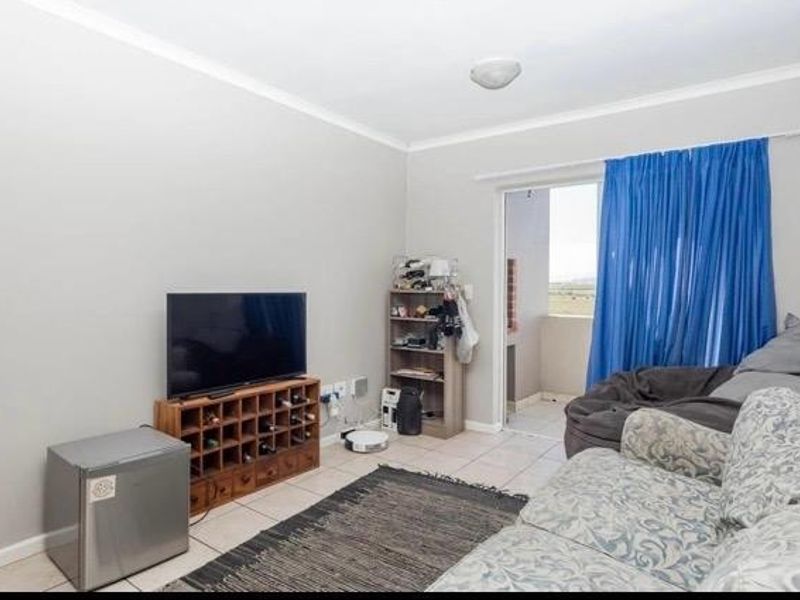 A functional living room featuring tiled flooring and a sliding glass door providing access to an outdoor balcony area.