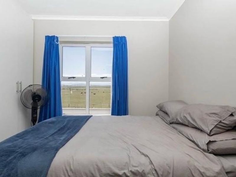 A functional bedroom featuring built-in cupboards and a window with views of the surrounding landscape.