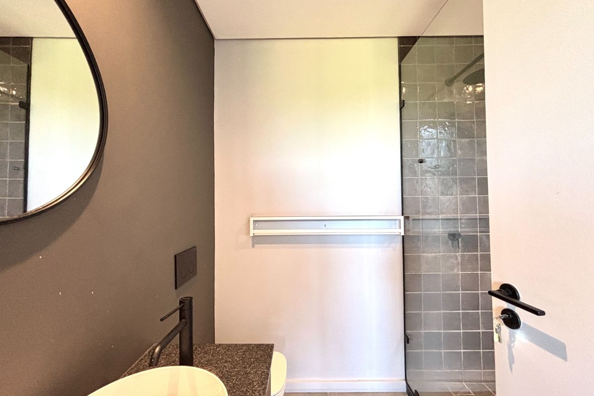 Modern bathroom featuring a vessel sink with black fixtures, stone vanity countertop, and a walk-in shower with tiled walls and glass screen.