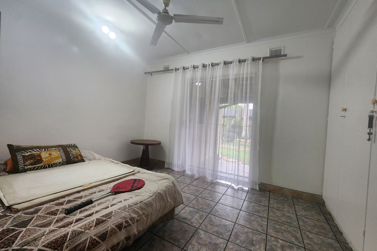 A bedroom featuring tiled flooring, a ceiling fan, and a sliding glass door providing access to the exterior.