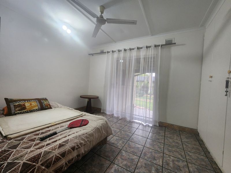A bedroom featuring tiled flooring, a ceiling fan, and a sliding glass door providing access to the exterior.