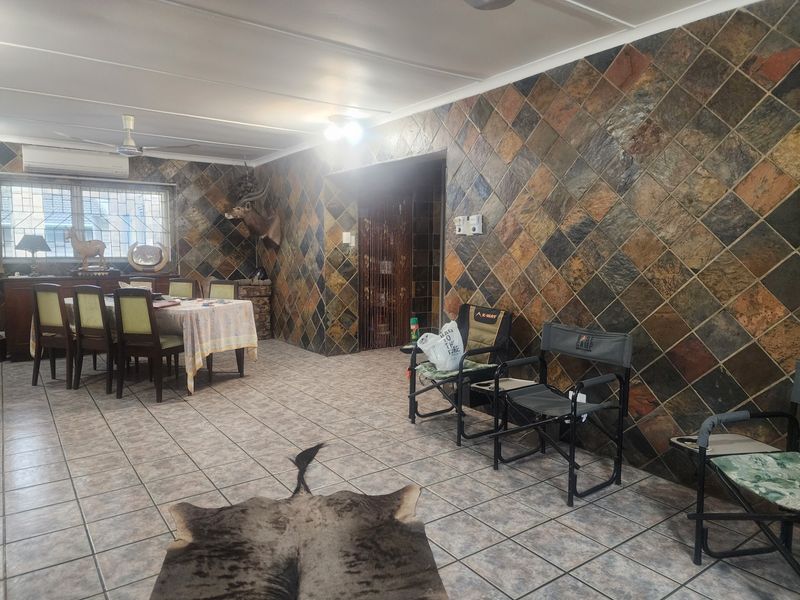 Spacious dining area featuring distinctive slate wall tiling, ceramic floor tiles, and integrated climate control, offering a functional space with significant potential for modernization.