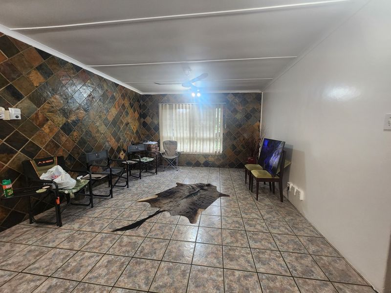 Spacious living area featuring a distinctive slate tile accent wall, ceramic floor tiling, and a ceiling fan.