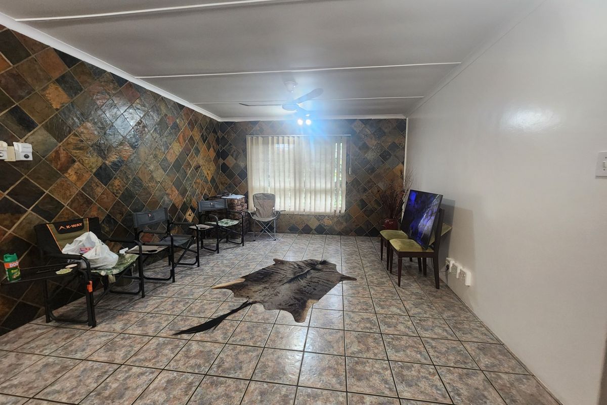 Spacious living area featuring a distinctive slate tile accent wall, ceramic floor tiling, and a ceiling fan.