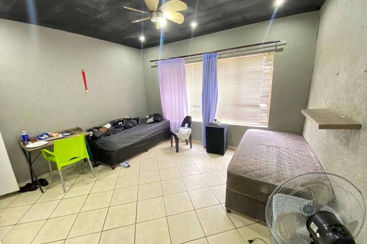 A bedroom featuring tiled flooring, a ceiling fan, recessed lighting, and venetian blinds. The room has a textured wall finish and a floating shelf.