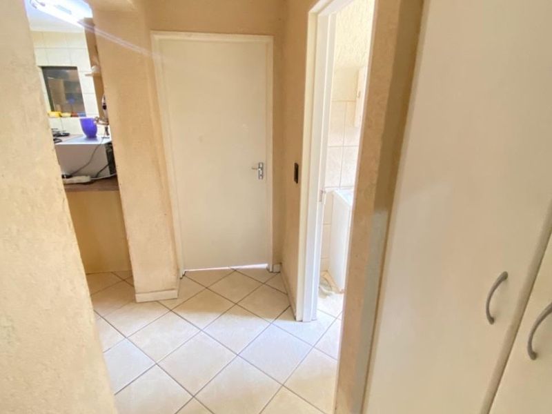 A functional hallway featuring tiled flooring and built-in storage cupboards, providing access to adjacent rooms within the apartment.