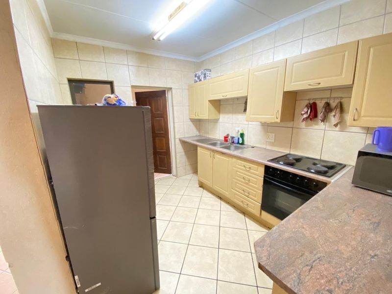A functional kitchen featuring built-in cabinetry, laminate countertops, a stainless steel sink, and an integrated electric stove and oven with tiled finishes.