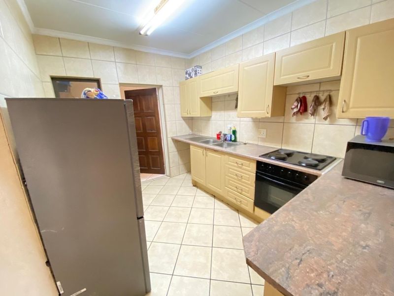A functional kitchen featuring built-in cabinetry, laminate countertops, a double basin sink, and a built-in electric stove and oven with tiled finishes.