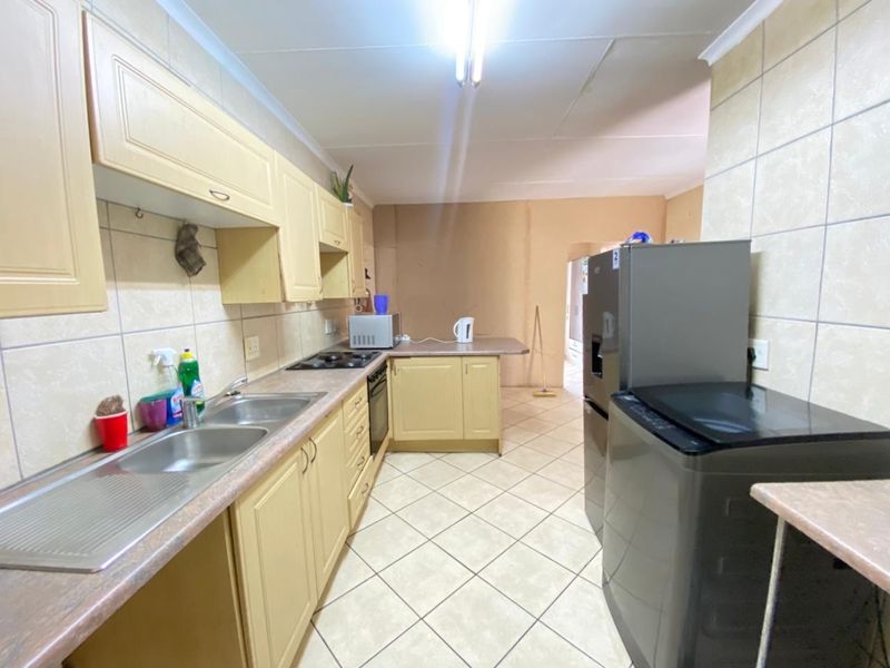 Functional kitchen featuring built-in cabinetry, laminate countertops, a double bowl sink, and integrated oven and hob, with tiled flooring and splashbacks.