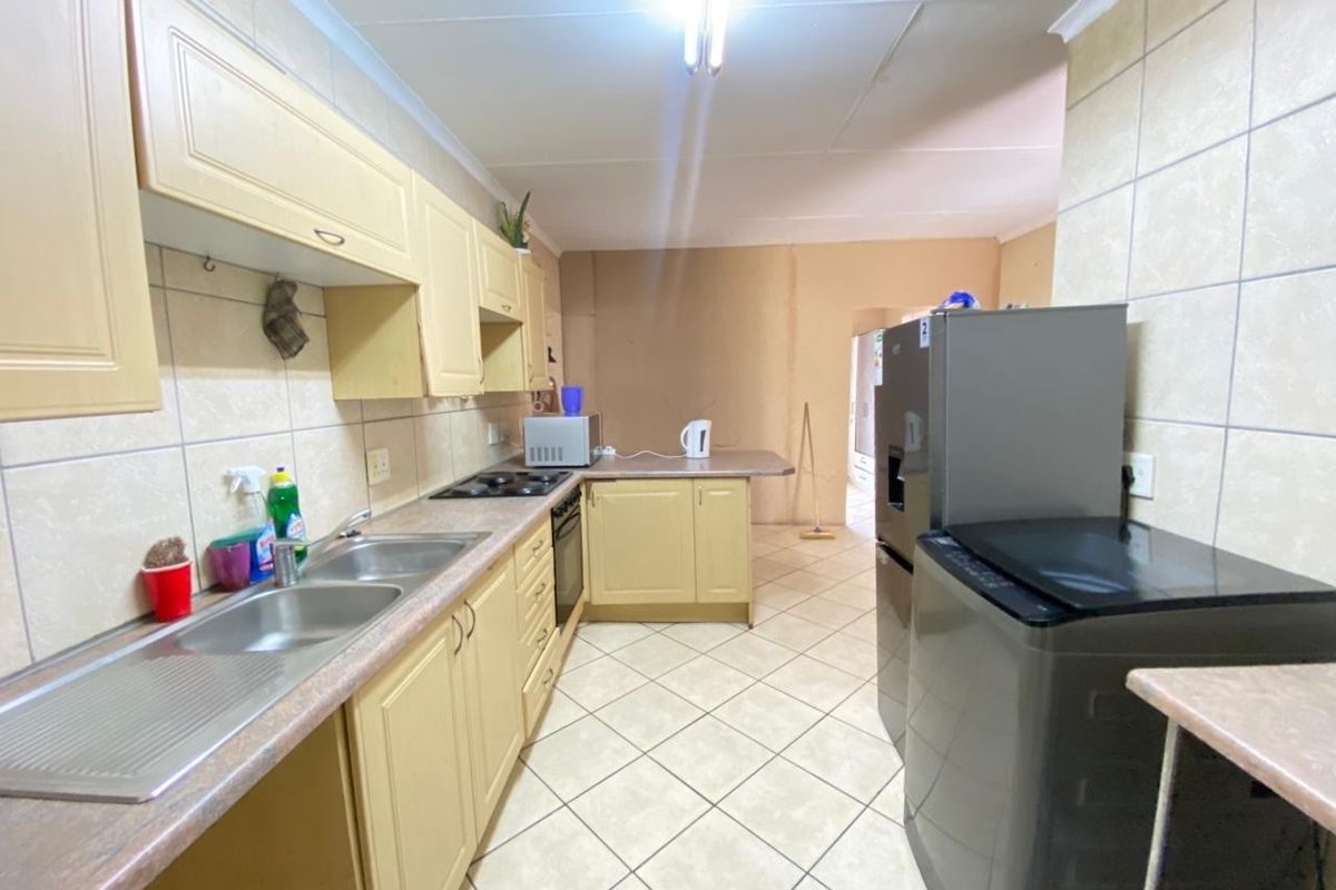 Functional kitchen featuring built-in cabinetry, laminate countertops, a double bowl sink, and integrated oven and hob, with tiled flooring and splashbacks.