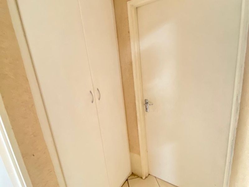A functional hallway featuring tiled flooring and a built-in storage cupboard, providing efficient access and storage space within the apartment.