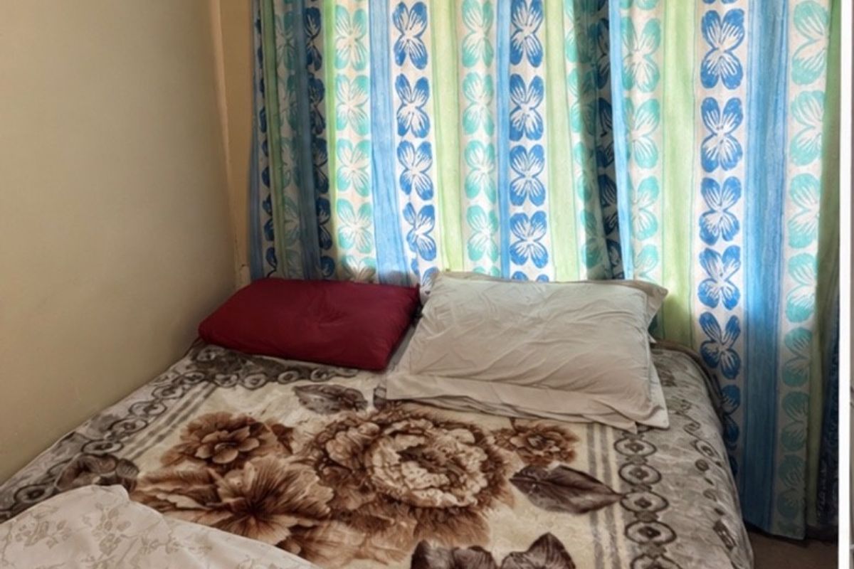 A compact bedroom featuring a window with patterned curtains.