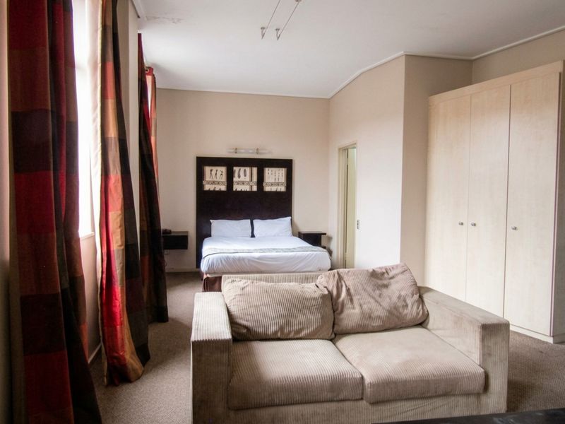 Spacious bedroom featuring built-in wardrobes, carpeted flooring, and neutral wall finishes, offering a functional layout with potential for modern updates.