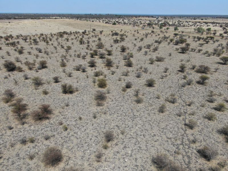 An aerial view of a large, undeveloped residential land plot featuring native scrub vegetation and open terrain.