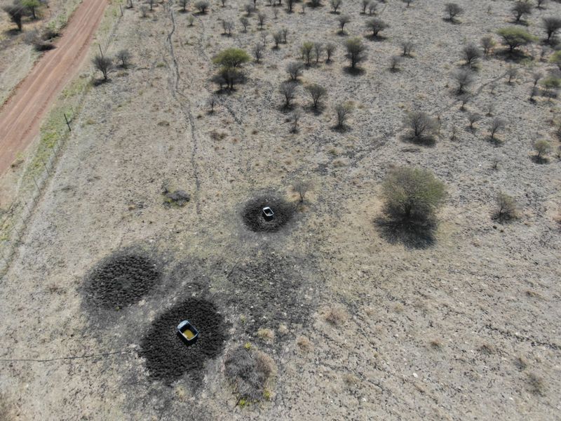 Aerial view of vacant residential land featuring a dirt access road, perimeter fencing, and established livestock water troughs in a natural bushveld setting.