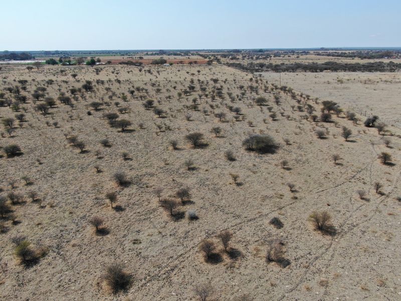 An aerial view of a large, undeveloped residential plot featuring native scrubland and open terrain.