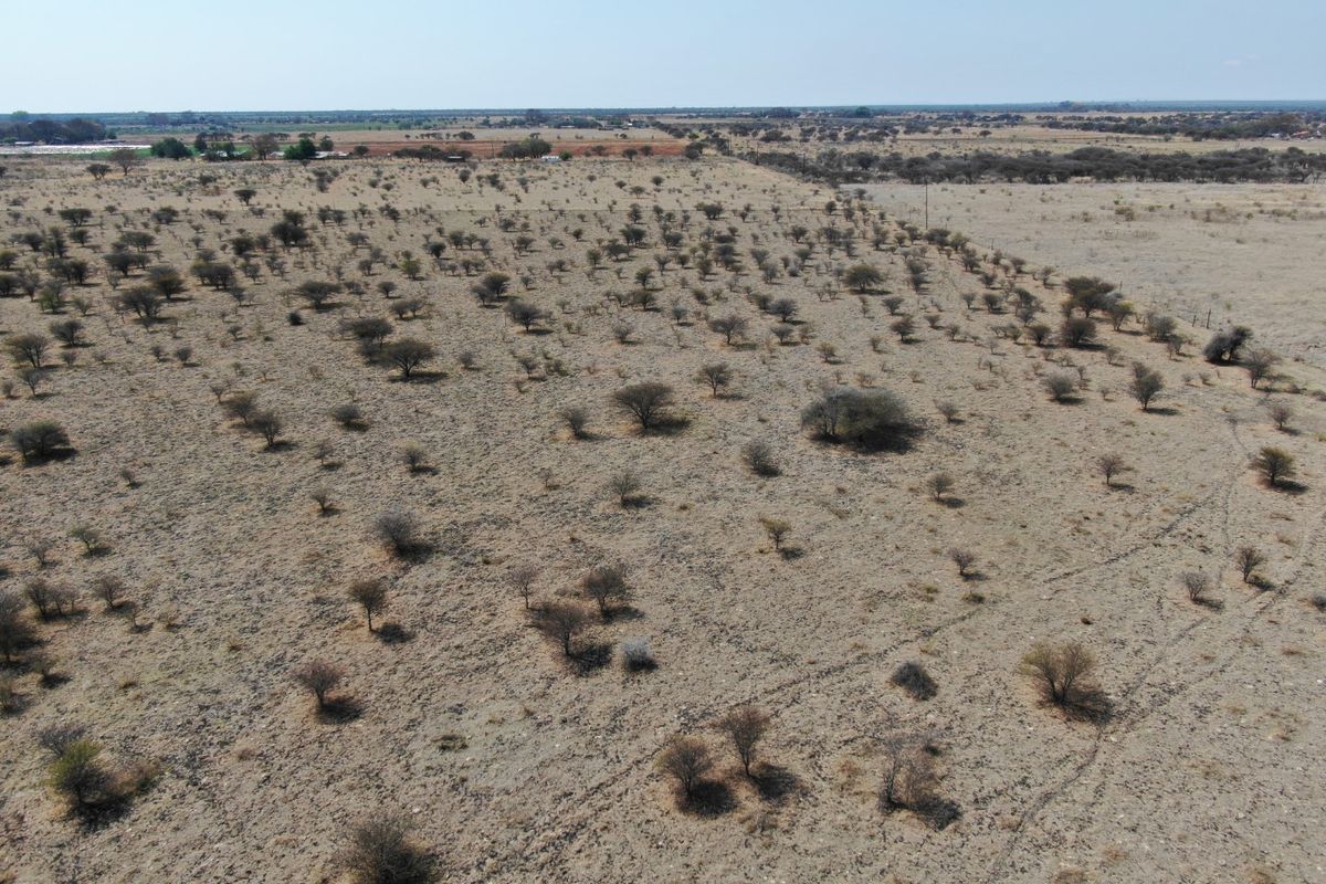 An aerial view of a large, undeveloped residential plot featuring native scrubland and open terrain.