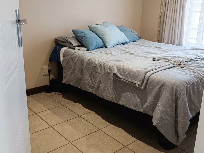 A functional bedroom featuring neutral wall tones and tiled flooring, providing a clean and simple living space.