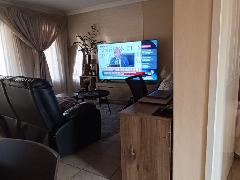 A living room area featuring tiled flooring and a sliding glass door with curtains, providing access to an outdoor space.